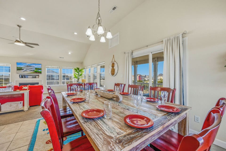 Gather around this expansive dining table with seating for your whole crew. Bright windows flood the space with natural light, creating a welcoming atmosphere for shared meals and memorable conversations.