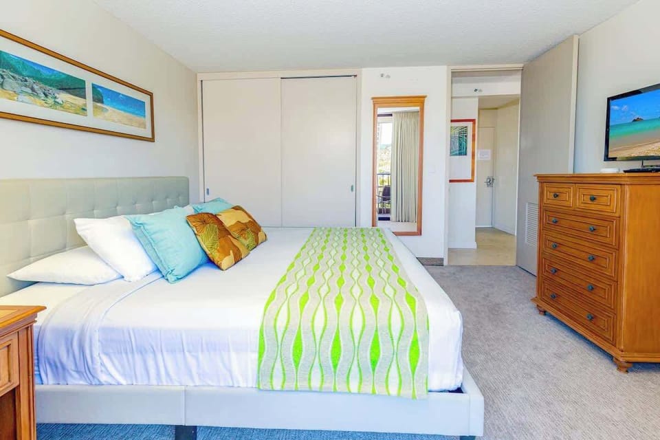Bright bedroom with a king-size bed and wooden dresser.