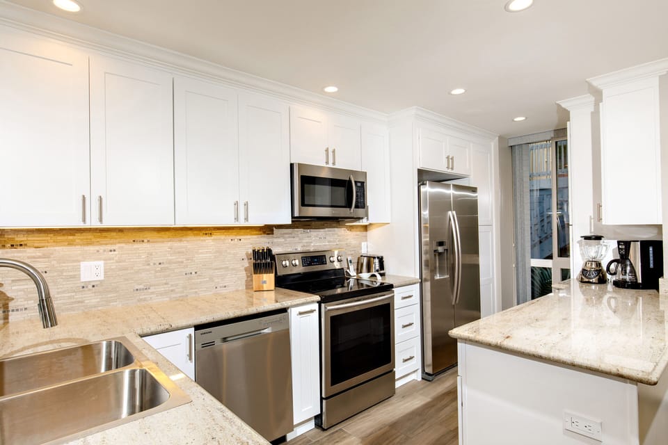 Kitchen - The remodeled kitchen features granite counters, stone back splash, stainless appliances, and a wood-look porcelain floor.