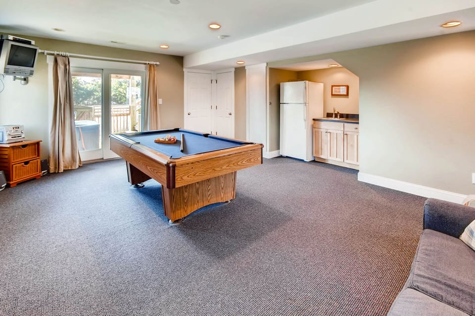 The spacious game room features a pool table and wet bar with refrigerator.