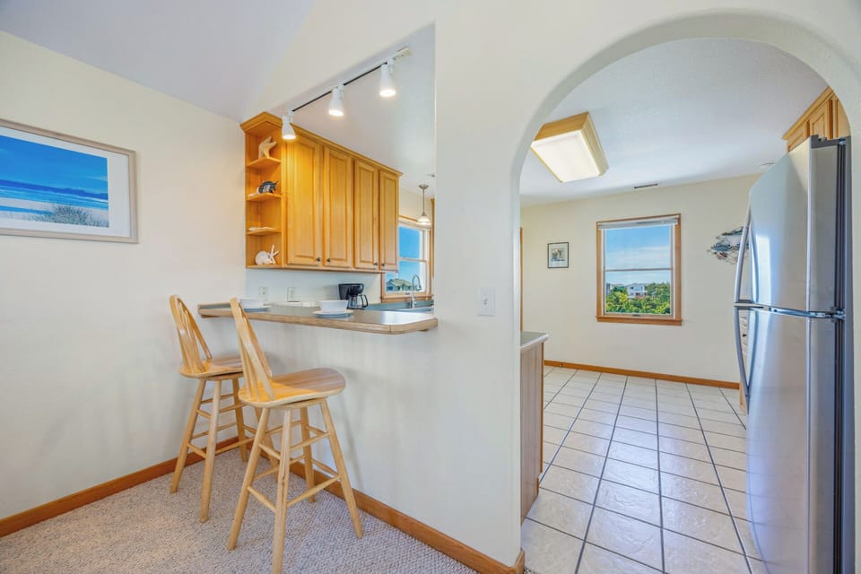 You'll love preparing meals in this bright, open kitchen with a cozy breakfast bar, plenty of cabinet storage, and modern stainless steel appliances—all beautifully lit by natural light.