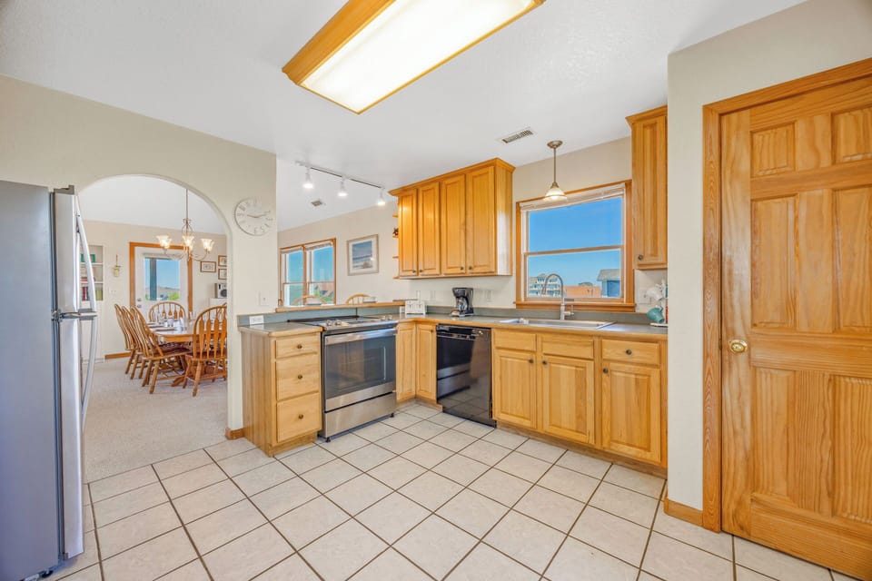 Step into your fully equipped kitchen with warm wood cabinetry, stainless steel appliances, and natural light from the skylight above, perfect for preparing your favorite meals during your stay.