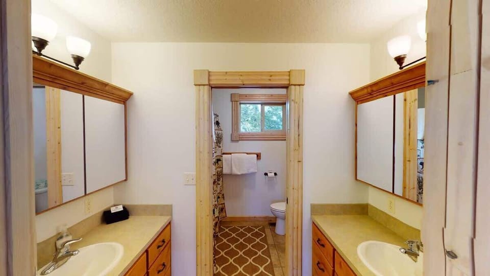Full size bathroom located upstairs with shower/tub combo, toilet, and two sets of sink vanities.