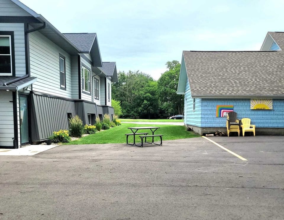 The grass area and front yard are designated for the Staycation, offering ample space for your group. It is equipped with chairs, a portable firepit, and a gas grill. The back parking lot is shared with the Stay Blu, that was the former parsonage. St