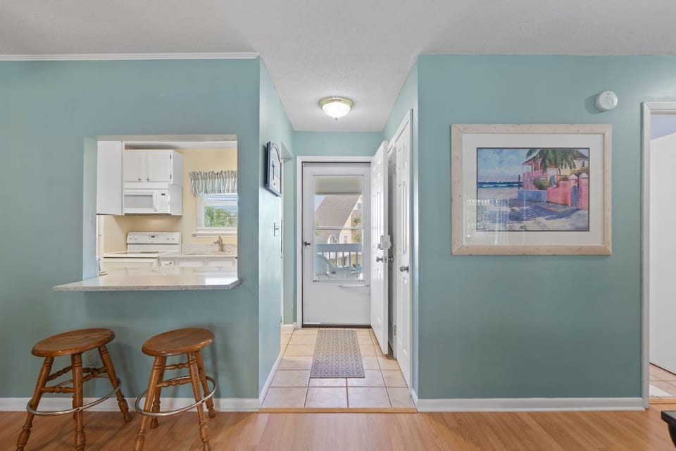 You'll love the open kitchen layout with breakfast bar seating and cheerful coastal artwork that creates a welcoming atmosphere.