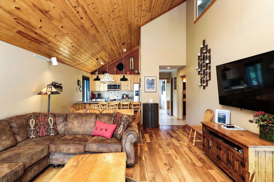 Relax in your spacious living area with soaring wood ceilings, cozy seating, and an open layout that flows into the kitchen and dining space—perfect for gathering together.