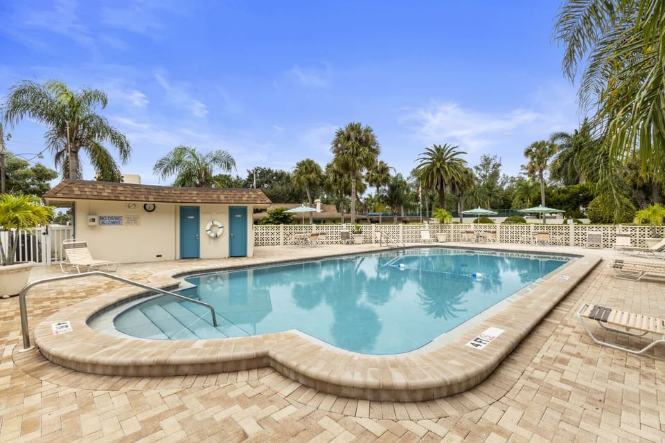 Community pool with building, deck chairs, and tropical palm trees