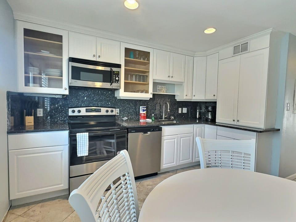 Kitchen with white cabinets, stainless appliances, and dark stone countertops