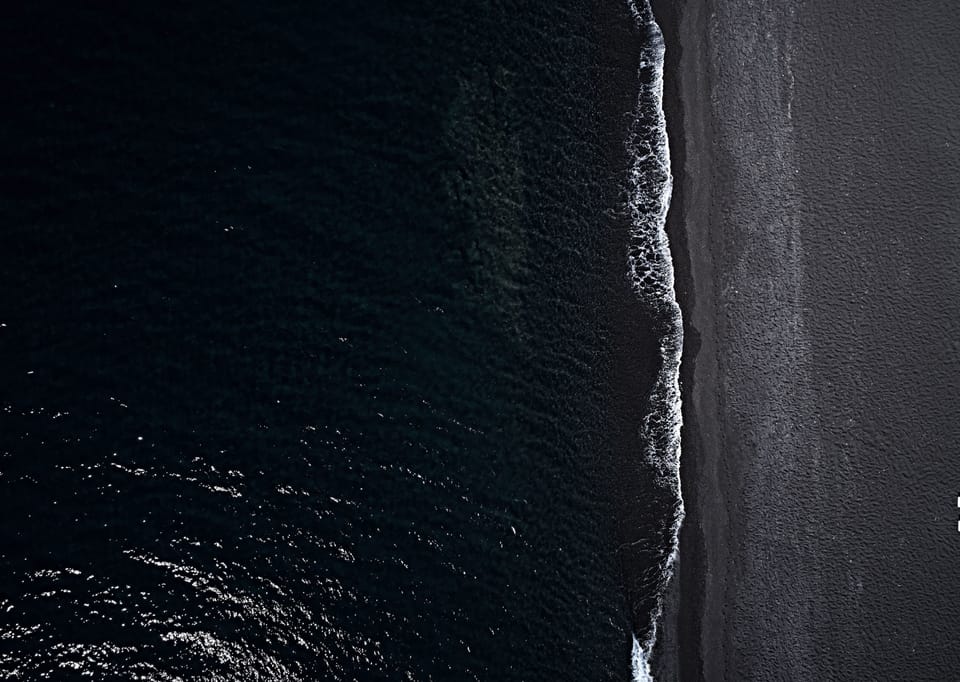 On the beach, black sand, sun loungers, beach towels