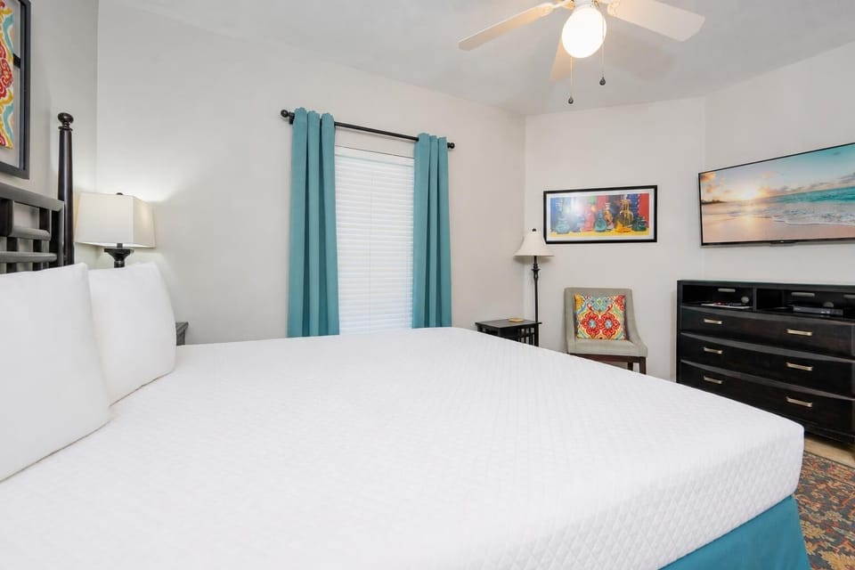 King bed in the guest suite invites you to unwind while watching a peaceful beach sunset on TV