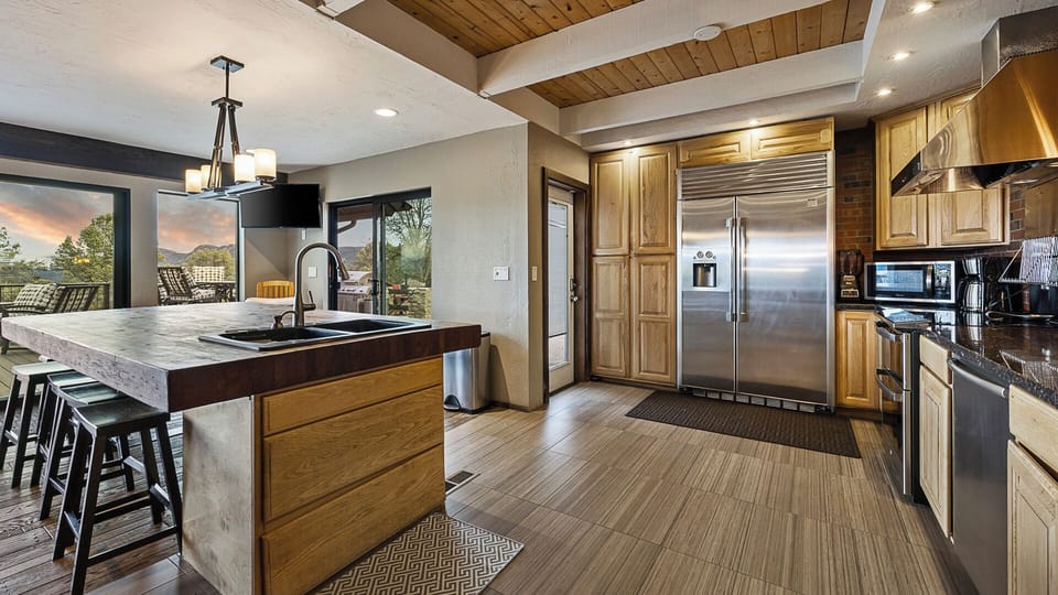 Stylish kitchen with a large island, wood accents, and scenic patio views.