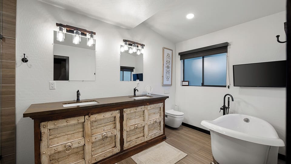 Cozy bathroom with a double vanity, freestanding tub, and warm decor.