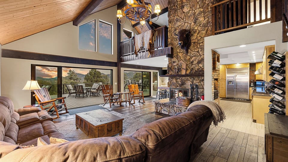 Rustic-chic living room with vaulted ceilings, stone fireplace, and deck views.