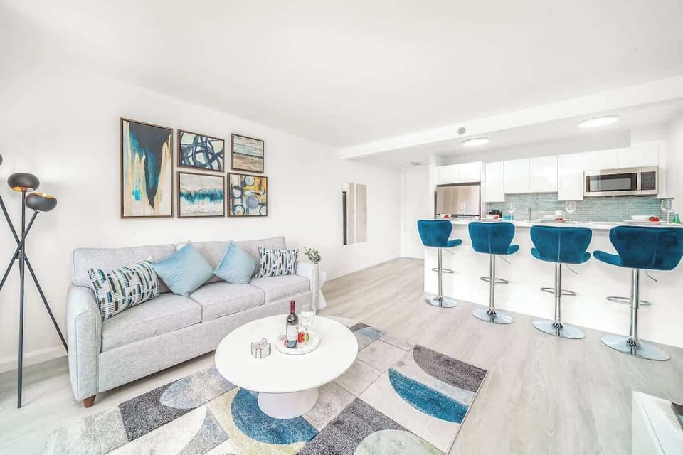 This bright and airy open-concept living area seamlessly connects the comfortable lounge area with a modern kitchen and breakfast bar, ideal for both relaxation and social gatherings.