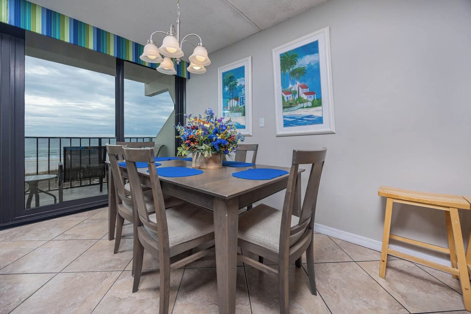 Enjoy meals at this dining area with a beautiful beachfront view, featuring a floral centerpiece and blue placemats