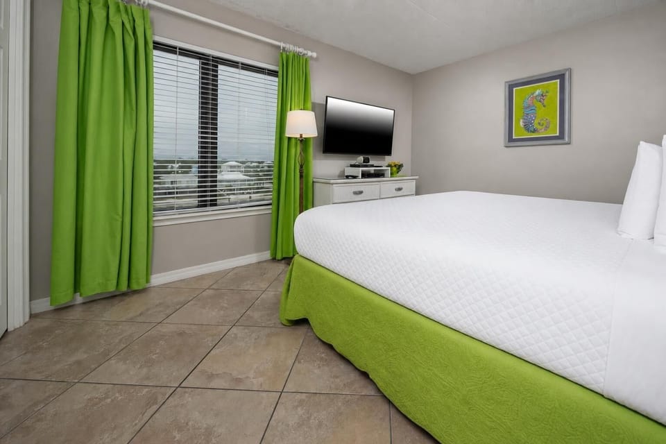 Cozy king guest suite with vibrant green accents and a lovely view through large windows