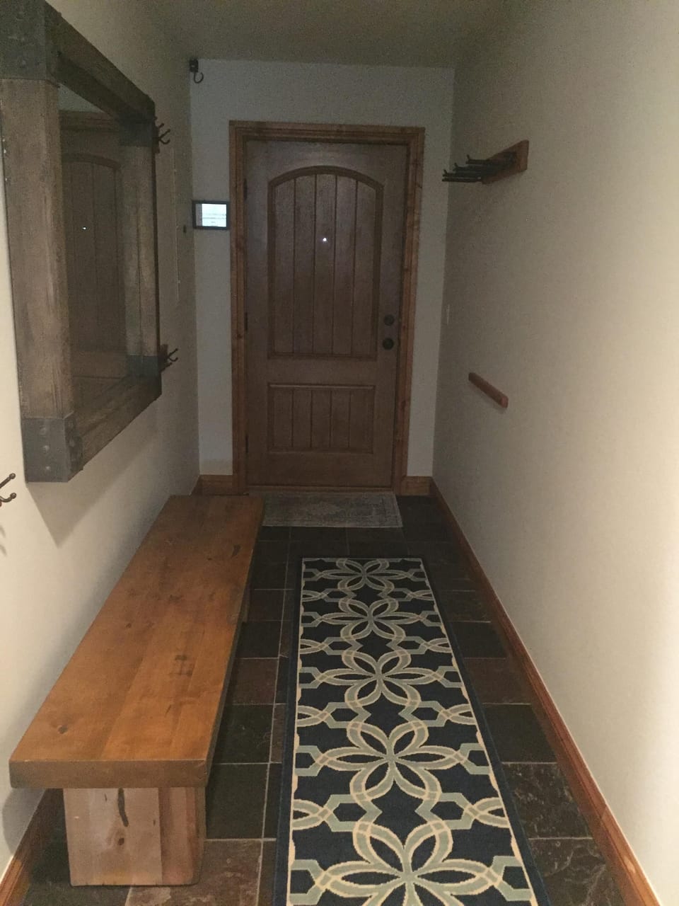 Entry hall looking at the door with bench/mirror/ski equipment racks.