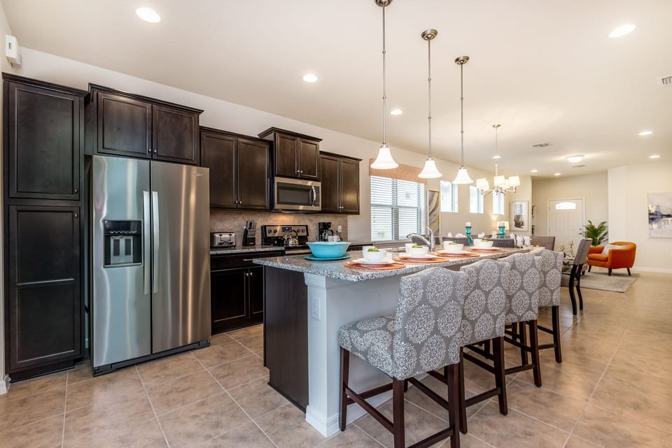 The kitchen, complete with a sleek counter bar table, transforms into a culinary hub where flavors mingle and conversations flow.