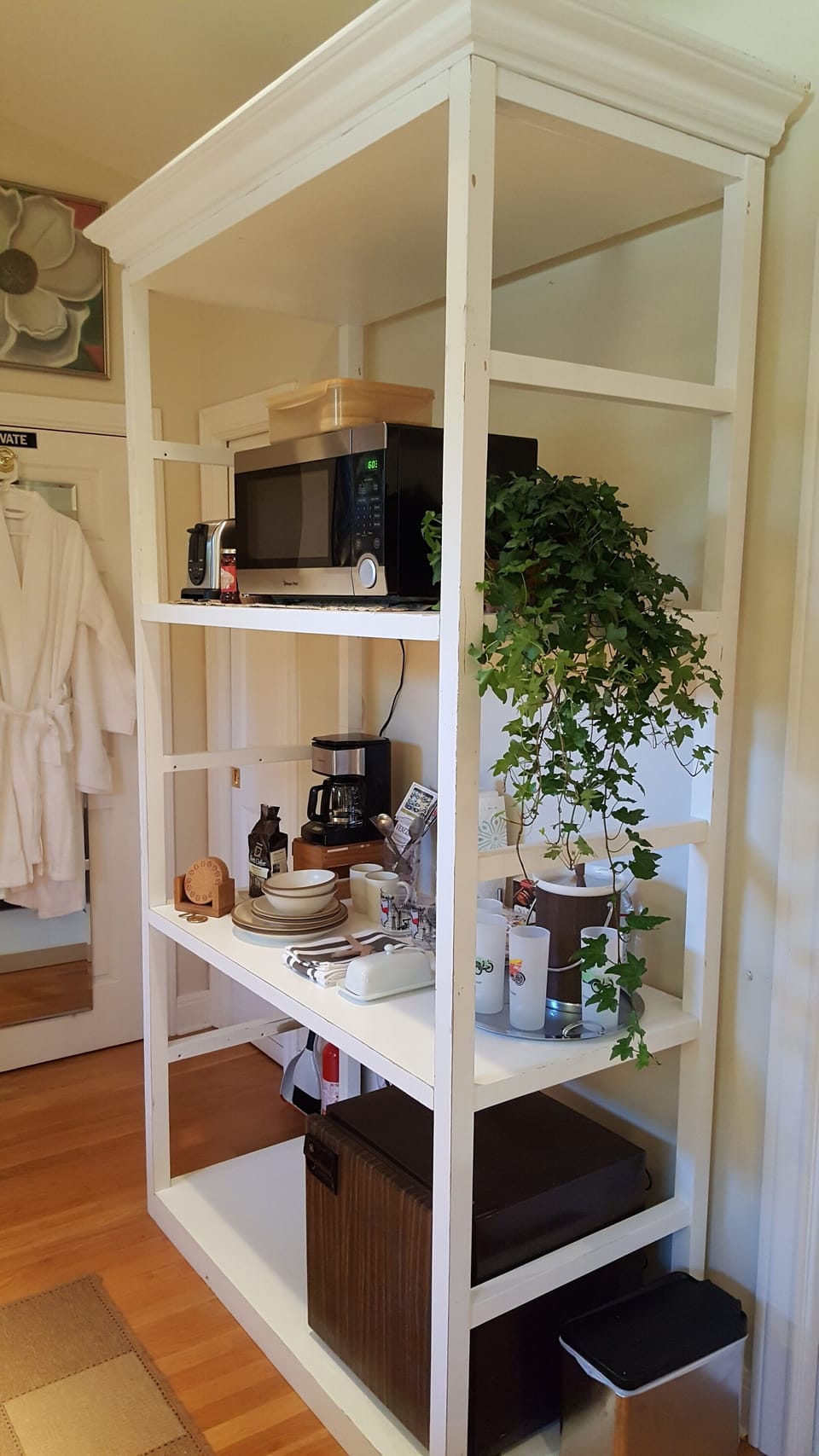 Kitchenette with coffee pot, microwave, stocked refrigerator, and dishes.