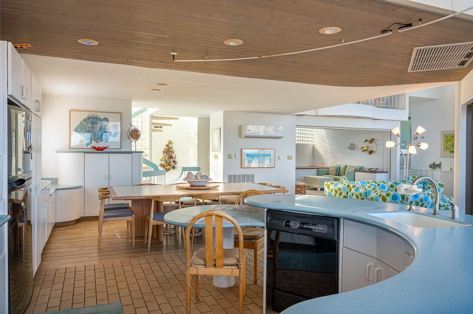 Kitchen view of large table, countertop seating and tv area.
