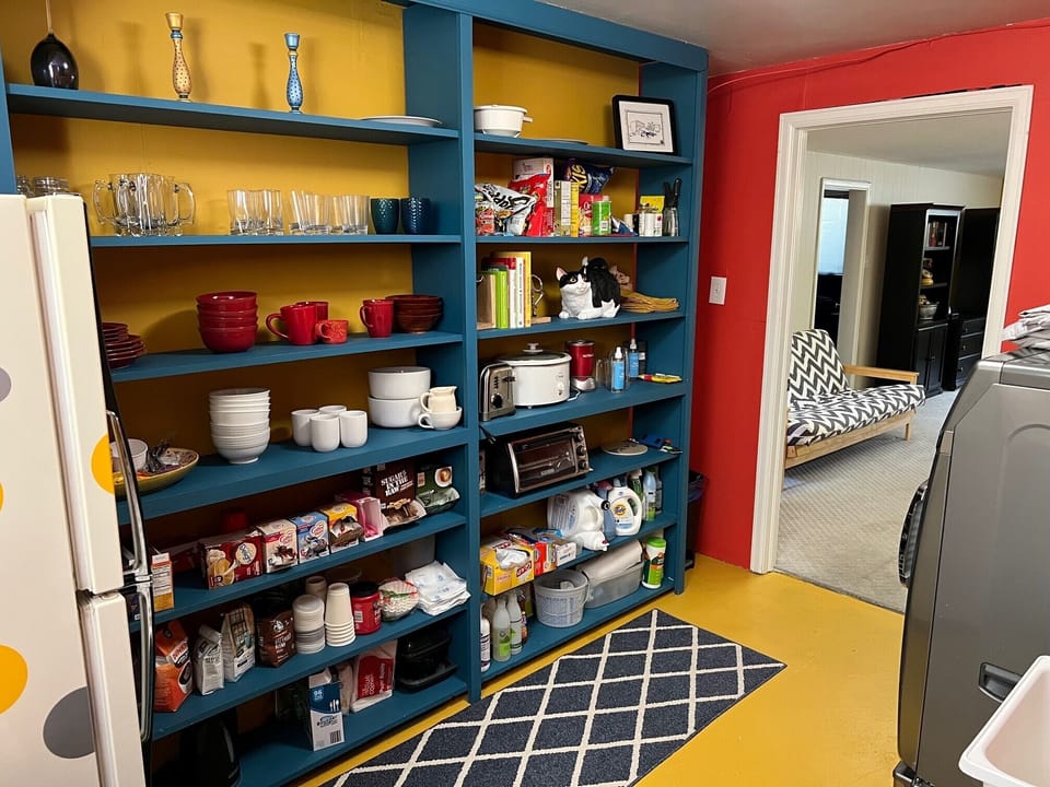 Kitchen open shelving. Well-stocked, full coffee bar, toaster oven, water jug.
