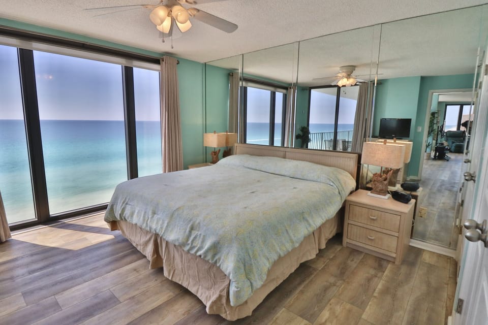 Master bedroom with a king size bed and floor to ceiling windows showing off the Gulf!