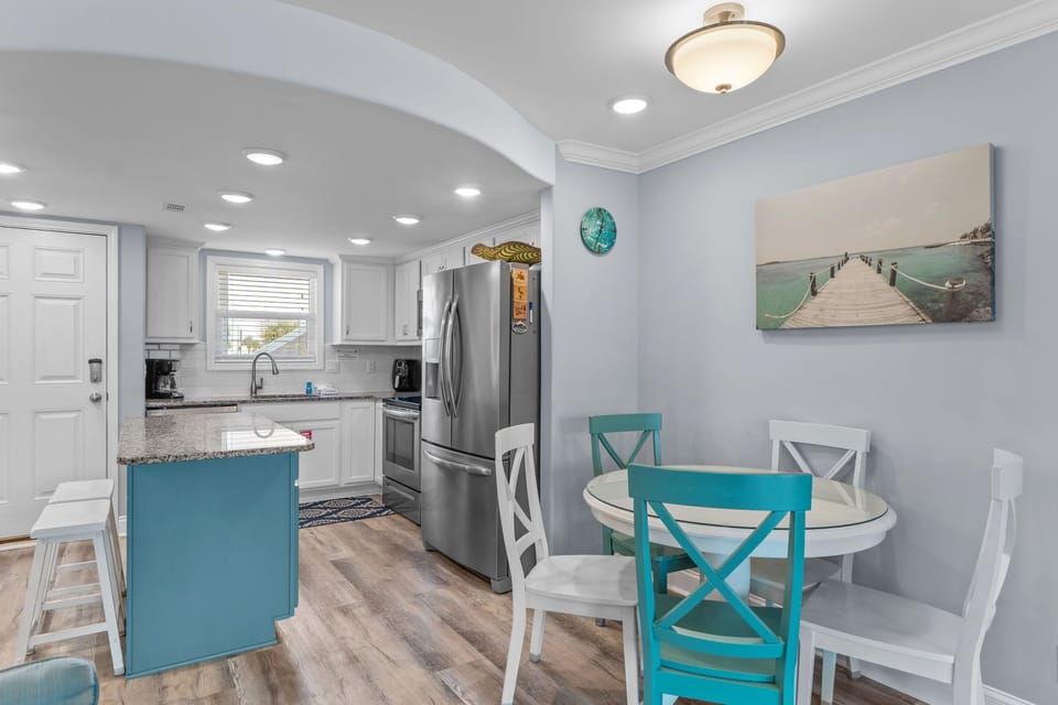 Gather around your bright dining table in this coastal-inspired open kitchen, where turquoise accents and modern appliances create the perfect space for morning coffee.