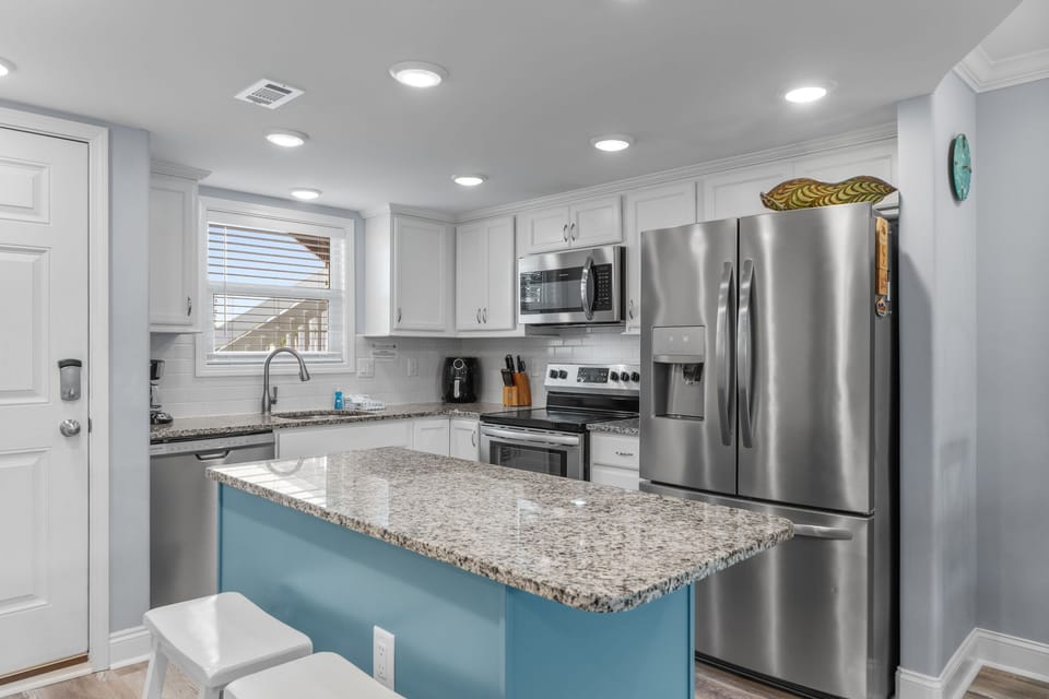 Your modern kitchen awaits with granite counters, stainless appliances, and a turquoise island perfect for morning coffee or meal prep.