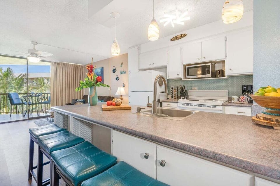 Fully equipped kitchen features white and stainless steel appliances, white cabinetry, breakfast bar, granite countertop