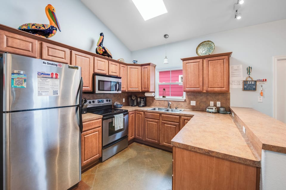 Cook your favorite meals in this fully equipped kitchen with modern appliances, ample counter space, and warm wood cabinetry.
