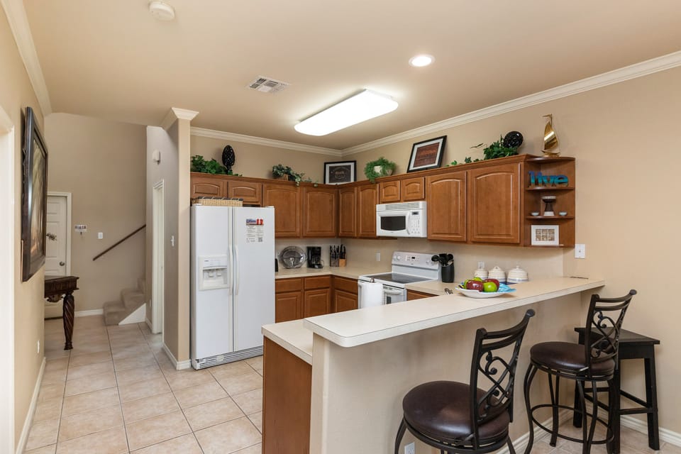 Your fully equipped kitchen awaits with warm wood cabinets, modern appliances, and a breakfast bar perfect for morning coffee or casual meals.