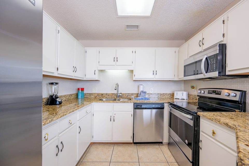 Modern kitchen featuring white cabinetry, granite countertops, and a breakfast bar for convenient entertaining