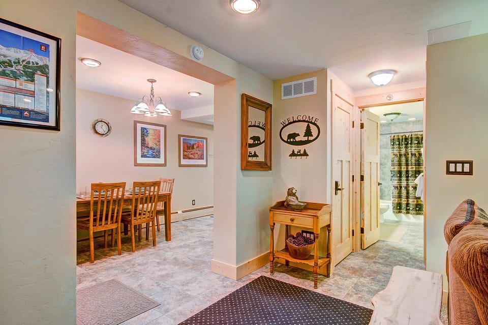 View of a home's entryway leading to a dining area. The entryway features a wooden console, wall decor with the word "Welcome," and a glimpse of a bathroom down the hall on the right.