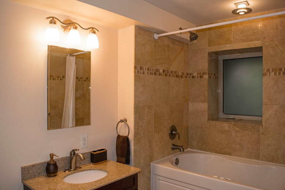 Heated Jacuzzi bathtub with natural marble and stone on lower level.