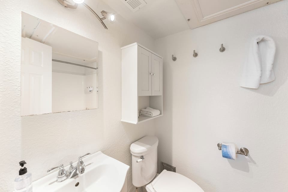Fresh white bathroom with everything you need - sink, toilet, and smart storage to keep your essentials organized.