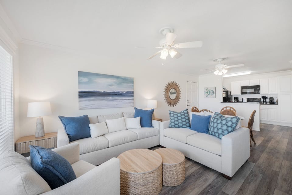 Relax in your bright, coastal-themed living space featuring plush sectional seating and seamless flow to the fully-equipped kitchen.