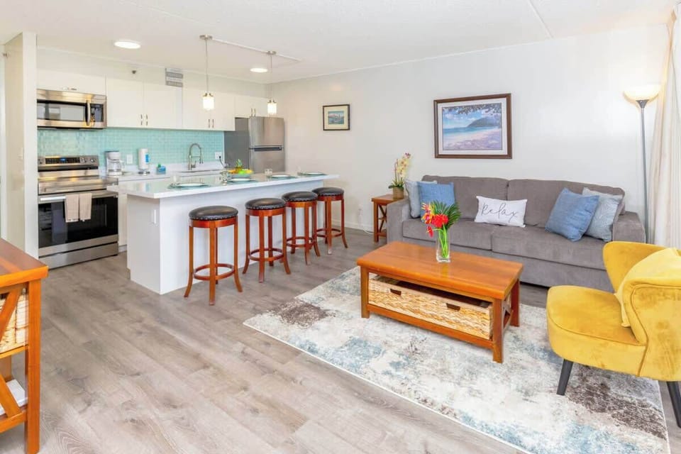An overview of the living room, kitchen, and dining area with 4 bar stools.