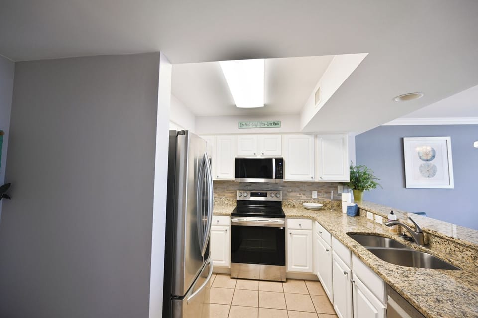 A stylish kitchen with granite countertops, stainless steel appliances, and whit