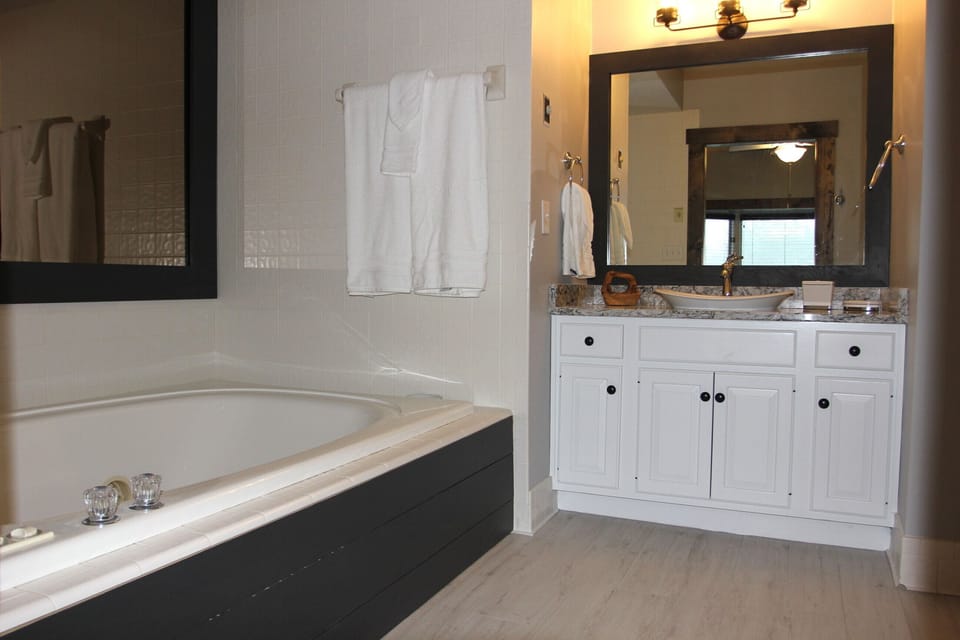 The jetted tub has a framed mirror and shiplap accents on the side
