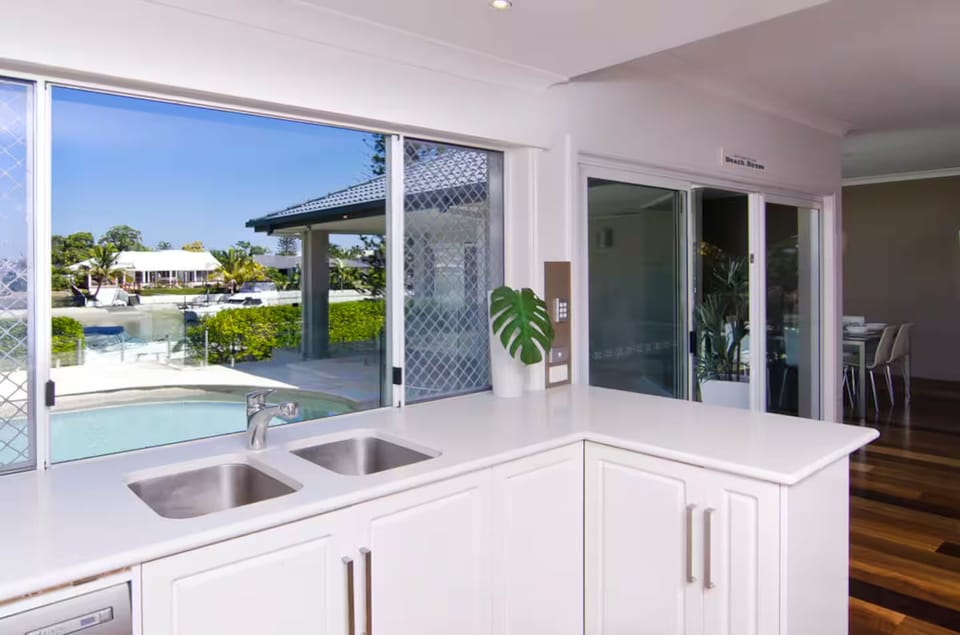 Kitchen with pool and water views beside the open living area