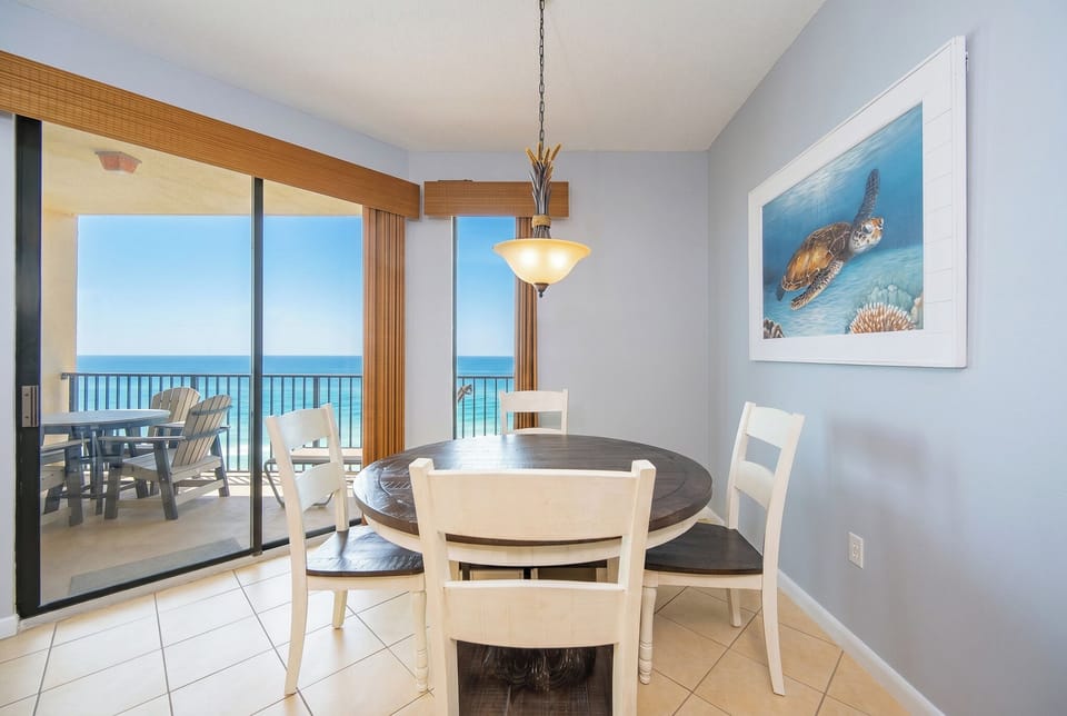Bright dining area featuring a round table with four chairs and panoramic views of the beach