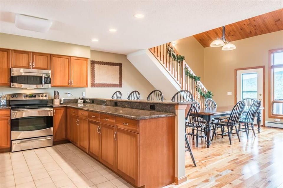 The fully equipped kitchen features granite countertops, stainless steel appliances, and a breakfast bar