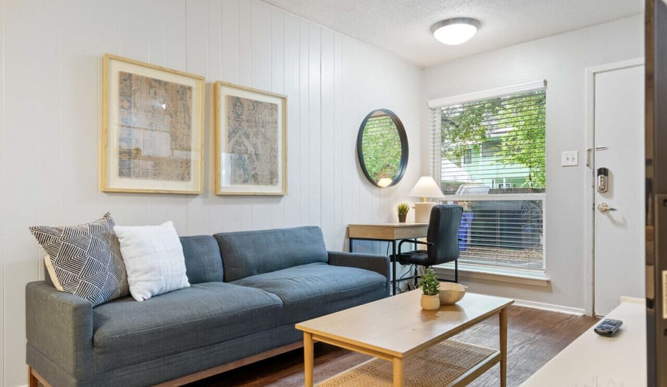 Studio apartment living area with comfortable sofa, work desk, and smart tv