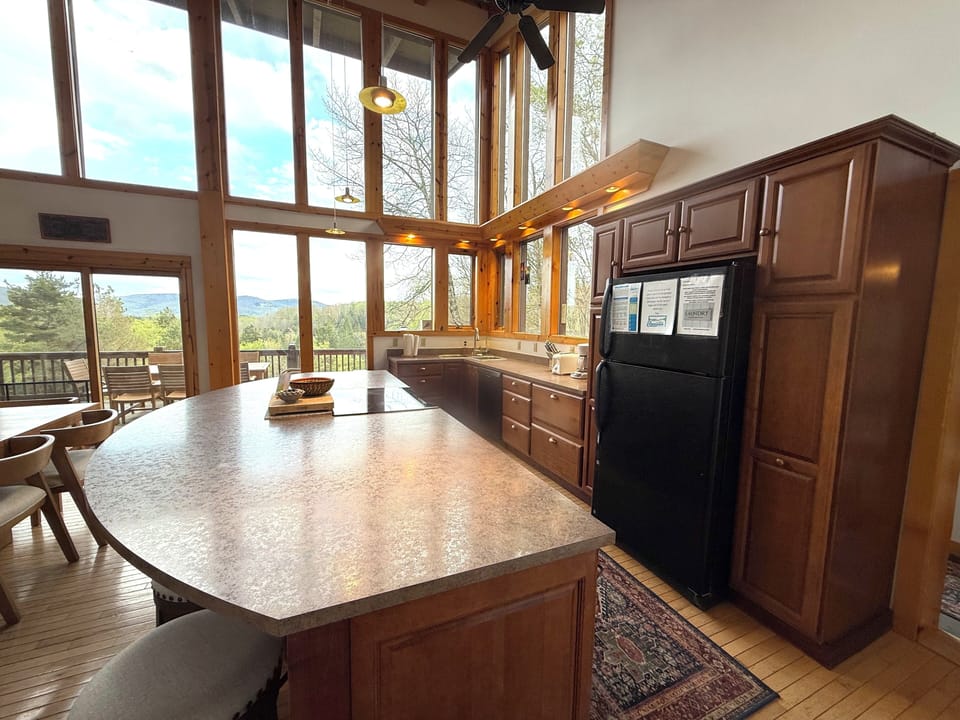 Prepare your favorite meals in this sun-filled kitchen featuring sleek countertops and modern appliances, all while soaking in stunning mountain views through floor-to-ceiling windows that frame nature's beauty.