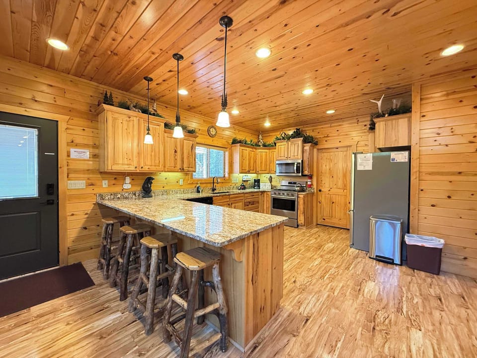 The fully equipped kitchen features gorgeous granite countertops and a spacious island with rustic log barstools, creating a perfect spot to gather.