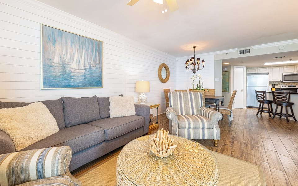 The inviting living area features a comfortable sofa with queen sleeper, stylish decor, and a view into the kitchen space