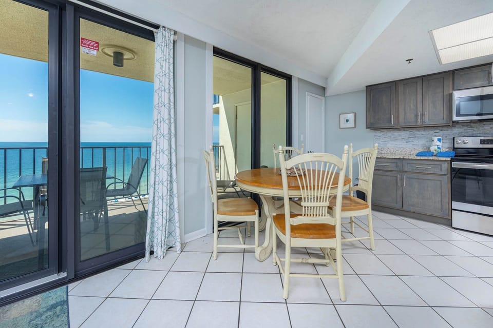 This inviting kitchen features stainless appliances, a cozy dining area, and a breathtaking view from the balcony