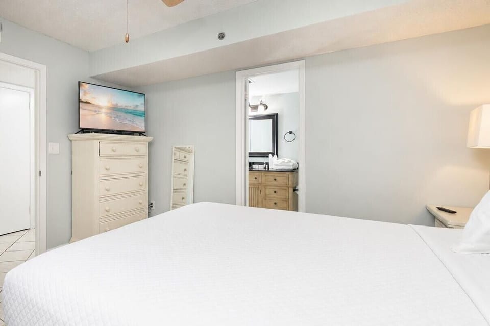 This cozy bedroom features a comfortable king bed, a TV for entertainment, and an adjoining bathroom with stylish cabinetry