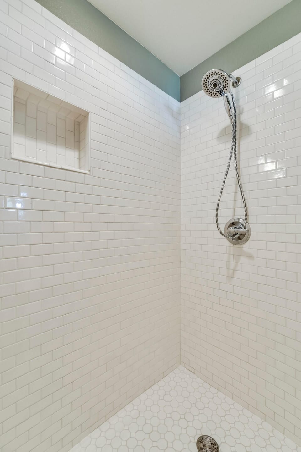 White subway tile adorns the walls/floor of the large walk-in shower. 