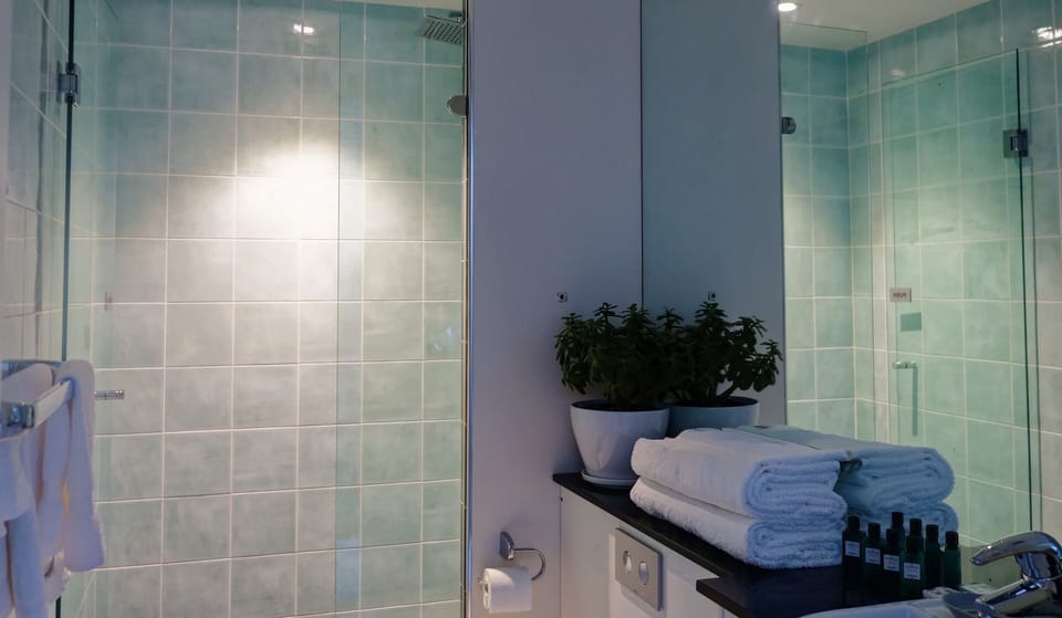 Bathroom with large rainwater head shower and plush towels for added luxury.